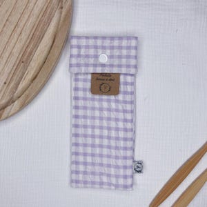 May include: A white and purple gingham fabric pouch with a button closure. The pouch has a label that says "Pochette brosse a dent".