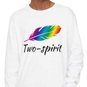 Könnte beinhalten: Weißes Langarmshirt mit einem Regenbogenfeder-Design und dem Text "Two-spirit" auf der Vorderseite.