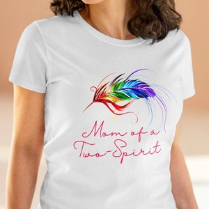 Könnte beinhalten: Weißes T-Shirt mit einem Regenbogenfeder-Design und dem Text "Mom of a Two-Spirit" in Pink.