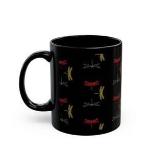 May include: Black ceramic coffee mug with a pattern of red, yellow, and white dragonflies.
