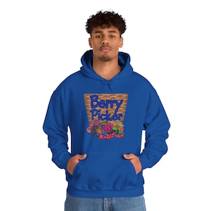 Op de afbeelding: Een koningsblauwe hoodie met een grafische print van een gevlochten bruine mand gevuld met diverse kleurrijke bessen, waaronder aardbeien, bosbessen en frambozen, met de tekst Berry Picker in blauwe letters boven het fruit afgebeeld.