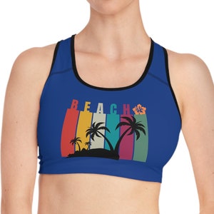 Peut inclure: Un soutien-gorge de sport bleu royal avec un dos nageur noir et un motif rétro coloré représentant des palmiers et le mot "BEACH".