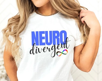 Puede incluir: Camiseta blanca con el texto "NEURO divergent" en letras azules y negras. Debajo del texto hay un símbolo de infinito con colores arcoíris.