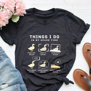 May include: Black t-shirt with a white graphic of ducks and the text "Things I do in my spare time". The graphic shows ducks being fed, looked at, researched, talked about, thought about, and dreamed about.