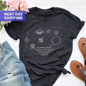 May include: Black t-shirt with a white graphic of the solar system and the text "The heavens declare the glory of God, and the sky above proclaims his handiwork. Psalm 19:1"