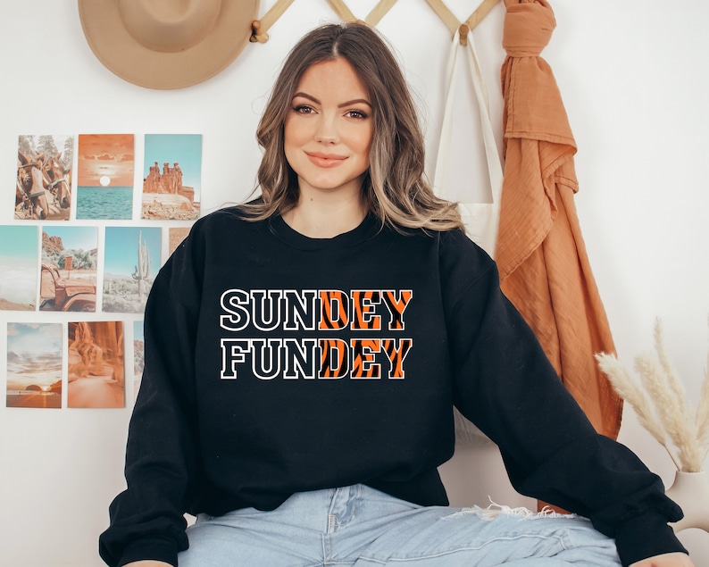 May include: Black sweatshirt with white text that reads "Sunday Funday" in a tiger stripe pattern.