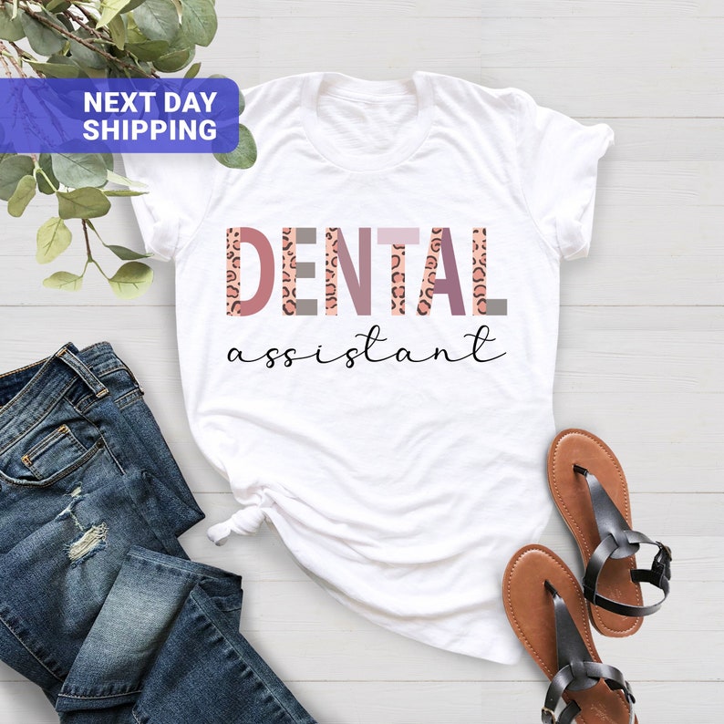 Peut inclure: T-shirt blanc avec le texte "DENTAL assistant" en lettres roses et grises avec un motif l&eacute;opard.
