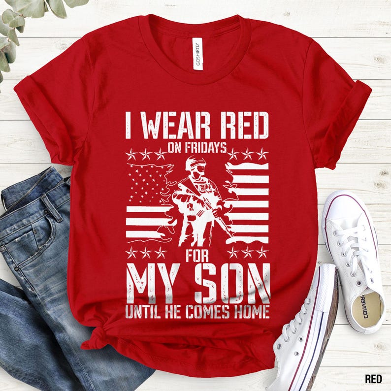 May include: A red short-sleeved t-shirt featuring a white graphic print of a soldier holding a rifle in front of an American flag. The text reads I WEAR RED ON FRIDAYS FOR MY SON UNTIL HE COMES HOME in a distressed, bold, white block font.