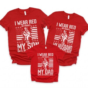 May include: Three red t-shirts with white graphic prints. Each shirt features a soldier silhouette, an American flag, and text reading I WEAR RED ON FRIDAYS FOR MY SON, MY HUSBAND, OR MY DAD UNTIL HE COMES HOME. The shirts have short sleeves and crew necks.