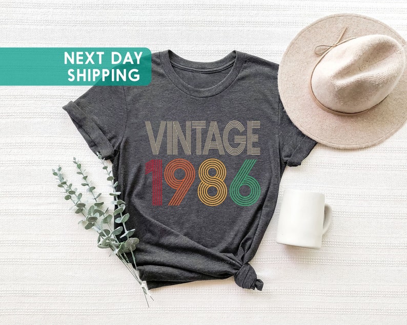 May include: A dark gray t-shirt with the text "Vintage 1986" in colorful retro-style font.