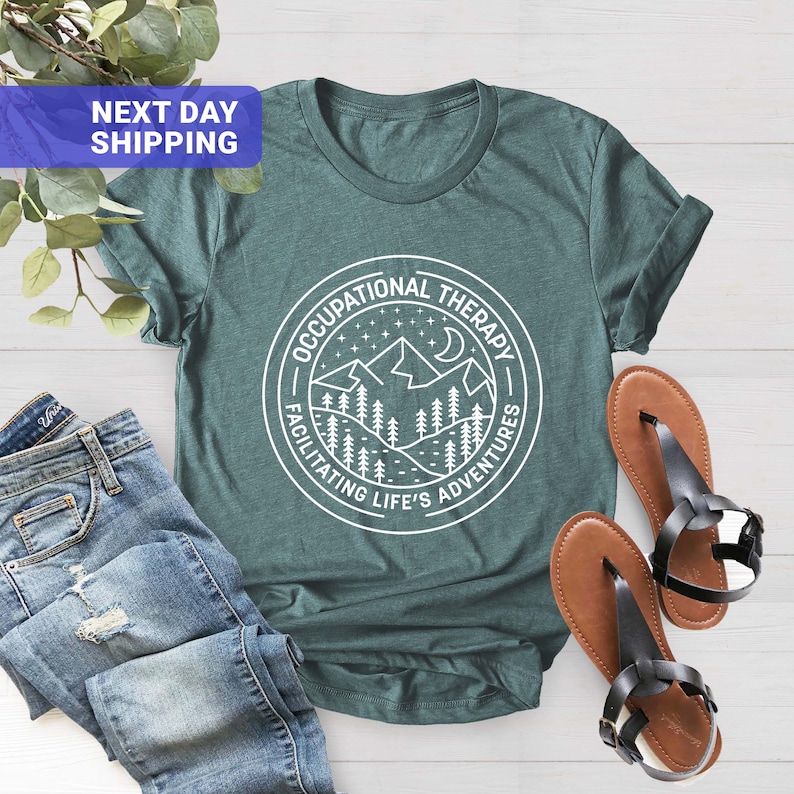 Op de afbeelding: Turquoise T-shirt met een witte afbeelding van een bergketen en de tekst "Occupational Therapy Facilitating Life's Adventures".