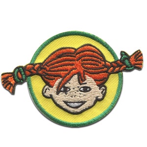 Puede incluir: Un parche bordado con una ni&ntilde;a de dibujos animados con el pelo rojo en trenzas, que lleva un c&iacute;rculo amarillo con un borde verde.