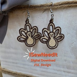 May include: Embroidered turkey earrings with brown and tan details. The earrings are on silver hooks and are displayed on a white wooden box with a gray bow and twine. The text "I SewNeedIt" is visible.