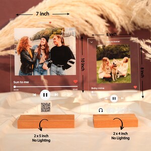 May include: Two acrylic photo frames with a music player design. The larger frame is 7 inches by 10 inches and the smaller frame is 5 inches by 8 inches. Both frames have a wooden base. The larger frame has a photo of three people and the text "Sun to me". The smaller frame has a photo of two people and a dog and the text "Baby mine".