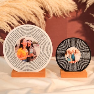 May include: Two round wooden plaques with a spiral of text and a photo of three friends in the center. The text on the plaques reads "Sweetest of the sunflowers, yeah, you're the sun to me".