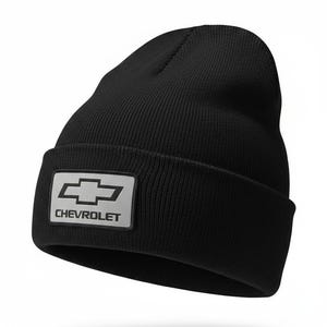 May include: Black knit beanie with a rectangular patch featuring the Chevrolet logo in white. The hat is a classic, cuffed style, suitable for cold weather. The Chevrolet logo is a silver bow tie.