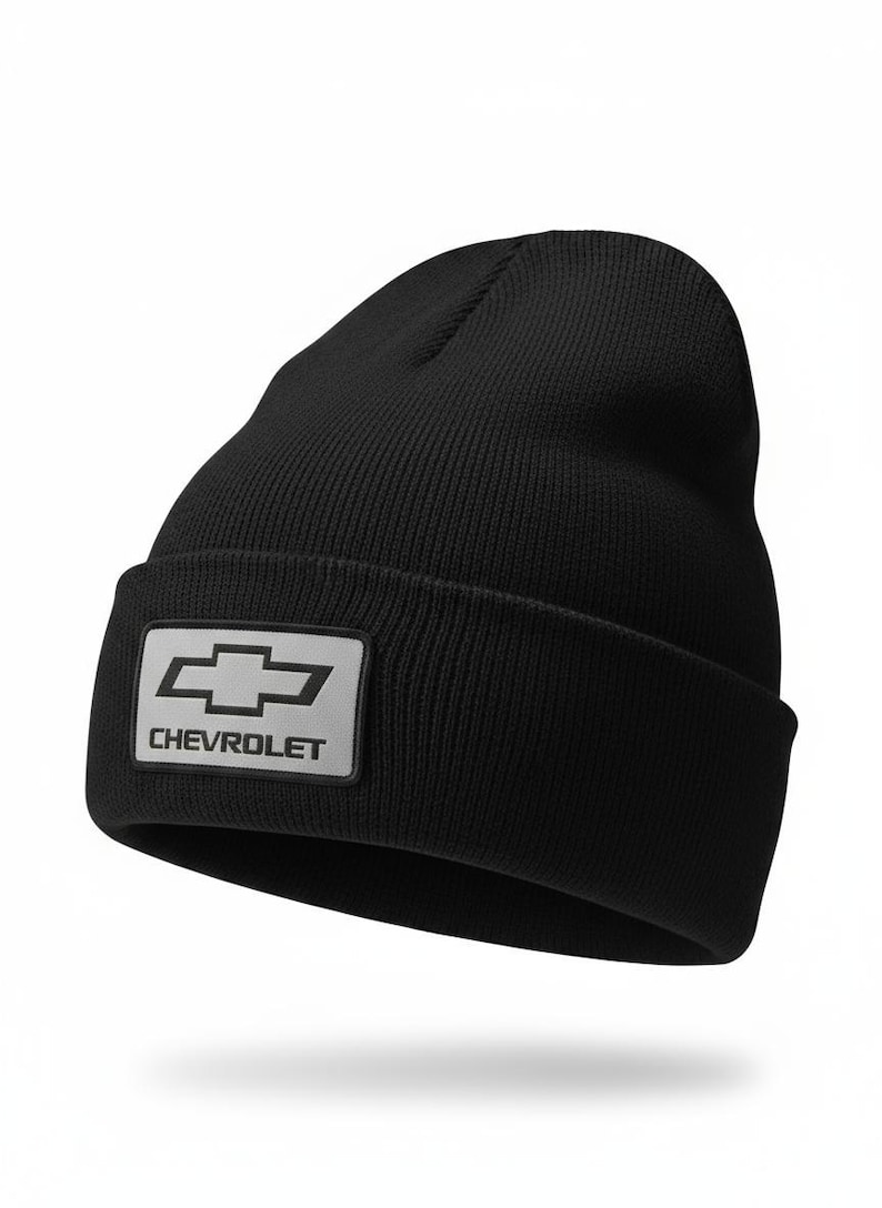 May include: Black knit beanie with a rectangular patch featuring the Chevrolet logo in white. The hat is a classic, cuffed style, suitable for cold weather. The Chevrolet logo is a silver bow tie.