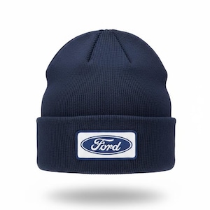 May include: Navy blue knit beanie with a rectangular patch featuring the Ford logo in white lettering on a blue background. The beanie has a ribbed texture and a folded brim.