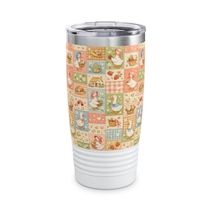 May include: A stainless steel tumbler featuring a repeating patchwork pattern of ducks wearing bonnets, small houses, strawberries, and flowers in soft pastel shades of pink, blue, green, and yellow, topped with a clear lid and a white base.