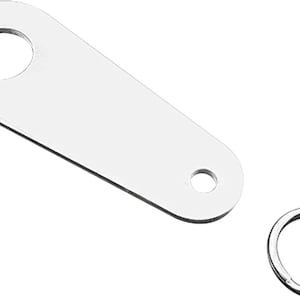 May include: A shiny, silver-colored metal key fob tag with a large circular hole and a smaller hole at the end. A separate silver key ring is also present.