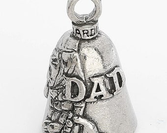 Puede incluir: Campana de plata con una mano sosteniendo una flor y la palabra "DAD" en el lateral. La campana tiene un lazo en la parte superior para colgarla.