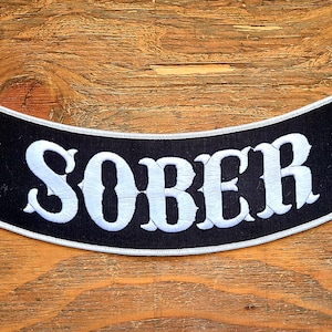 May include: Black and white embroidered patch with the word "SOBER" in white lettering on a black background.
