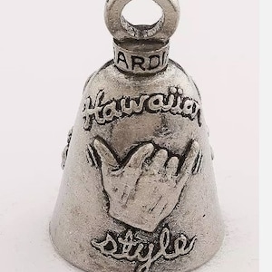 May include: Silver bell with a raised inscription that reads "Hawaiian Style" and a raised image of a hand gesture. The bell has a loop at the top for hanging.