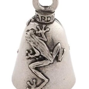 May include: A silver-colored bell with a frog design. The bell has a loop at the top for hanging and the word "GARD" is visible. The frog is depicted in a detailed, realistic style, clinging to the bell's surface.