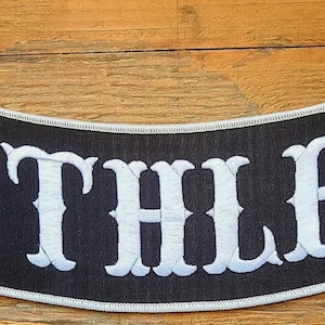 May include: Black and white embroidered patch with the word "Ruthless" in white lettering.