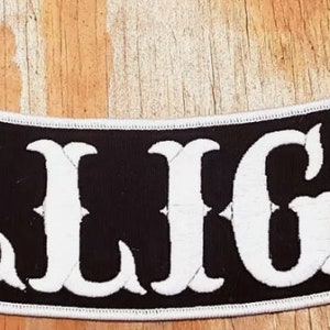 May include: Black and white embroidered patch with the text "DILLIGAF" in a curved, stylized font.