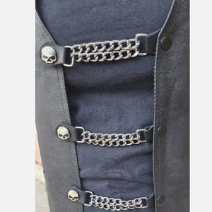 May include: Black leather vest with three sets of silver skull-shaped snaps and double chain straps.