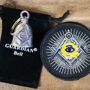 May include: A silver bell with a Masonic symbol on it, in a black velvet pouch. The bell is attached to a silver key ring. A black patch with a white Masonic symbol and a yellow eye is also shown.