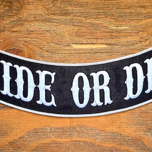 May include: Black and white embroidered motorcycle patch with the text "RIDE OR DIE" in a white font.