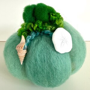 May include: A green felt pumpkin decorated with a seashell, a sand dollar, and green yarn accents.
