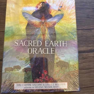 May include: A rectangular box set titled Sacred Earth Oracle by Toni Carmine Salerno and Leela J. Williams with artwork by Helena Nelson-Reed. The cover features a central figure with butterfly wings, surrounded by bison and vibrant colours.
