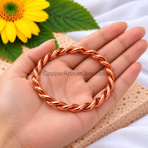 Handgemaakte gedraaide armband van puur koper, stapelbaar met een tensorring-effect.