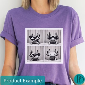 May include: Purple t-shirt with a graphic of four axolotls wearing sunglasses. Each axolotl is in a separate square. The axolotls are black and white.