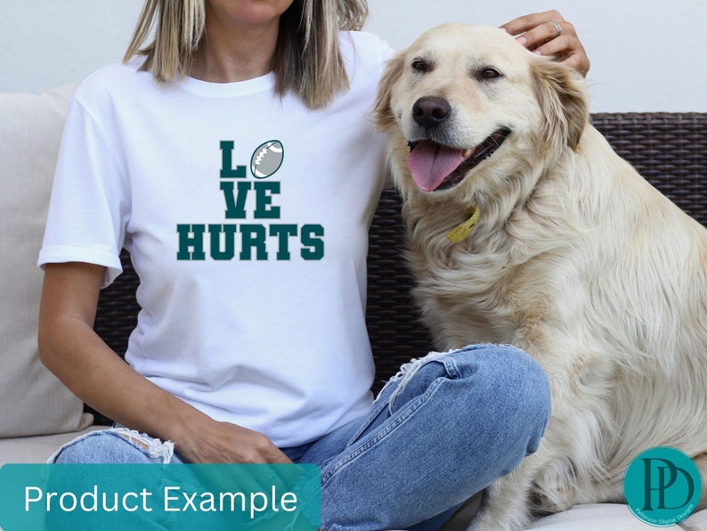 K&ouml;nnte beinhalten: Wei&szlig;es T-Shirt mit einem gr&uuml;nen Football und dem Text "LOVE HURTS" auf der Vorderseite. Eine Person tr&auml;gt das T-Shirt und sitzt mit einem Hund.