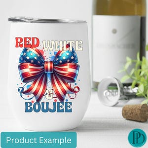 May include: A white stemless wine tumbler with a patriotic design. The tumbler features a red, white, and blue bow with the words "Red White & Boujee". A bottle of wine, a cork, and greenery are in the background.