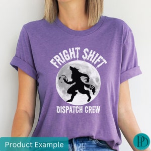 May include: Purple t-shirt with a white graphic of a werewolf holding a phone with the text "FRIGHT SHIFT DISPATCH CREW" and "911" on the moon.