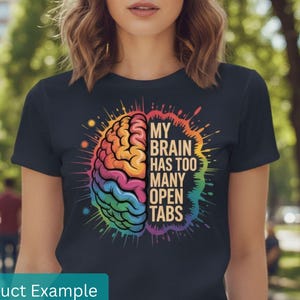 May include: Navy blue t-shirt featuring a colorful brain graphic with the text "MY BRAIN HAS TOO MANY OPEN TABS". The brain illustration is in shades of orange, yellow, green, blue, and purple. The shirt is a casual wear item.