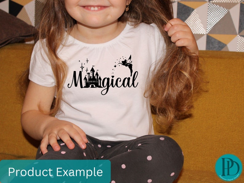 May include: A white t-shirt with a black silhouette of a castle and a fairy with the text "Magical" printed on it. The shirt is being worn by a child.