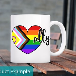Puede incluir: Taza de cerámica blanca con un corazón arcoíris y la palabra "ally" en letra negra.