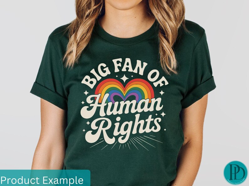 May include: Dark green t-shirt with the text "BIG FAN OF Human Rights" in a retro font, featuring a rainbow heart design. The shirt has rolled-up sleeves and a crew neck.