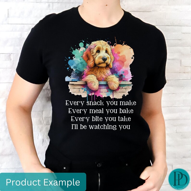 May include: A black t-shirt with a watercolor illustration of a golden doodle dog peeking over a brick wall. The text "Every snack you make Every meal you bake Every bite you take I'll be watching you" is printed on the shirt.