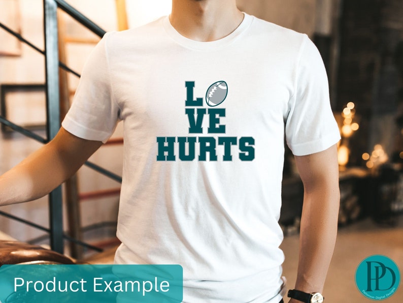K&ouml;nnte beinhalten: Wei&szlig;es T-Shirt mit einem blauen und grauen Football-Motiv und dem Text "LOVE HURTS".