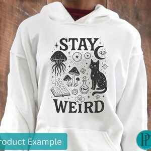 May include: White hoodie with a black graphic design featuring a cat, mushrooms, and the words "STAY WEIRD". The design includes a jellyfish, an open book, and other mystical elements. The hoodie has a front pocket and a drawstring hood.
