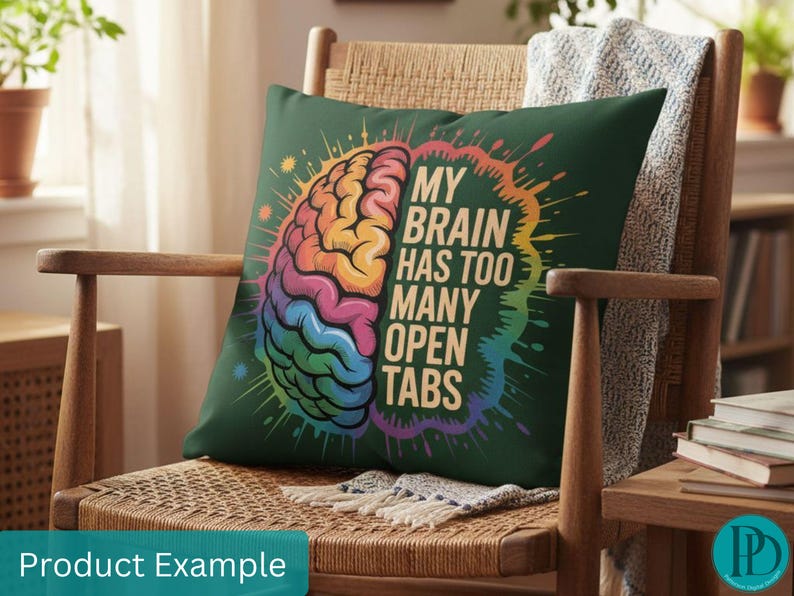 May include: A dark green throw pillow with a colorful brain graphic and the text "MY BRAIN HAS TOO MANY OPEN TABS." The brain illustration features rainbow colors. The pillow is on a wooden chair with a woven seat.