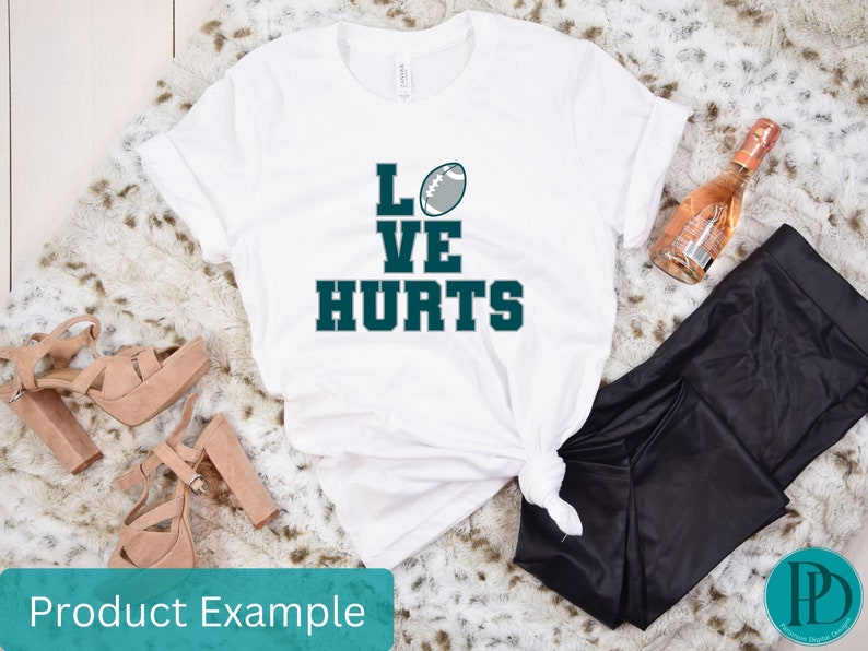 K&ouml;nnte beinhalten: Wei&szlig;es T-Shirt mit dem Text "LOVE HURTS" in Gr&uuml;n und einer Fu&szlig;ballgrafik.