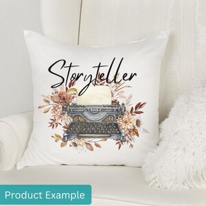May include: White throw pillow with the word "Storyteller" in black script. A vintage typewriter with a sheet of paper is surrounded by watercolor flowers in shades of brown, orange, and cream.